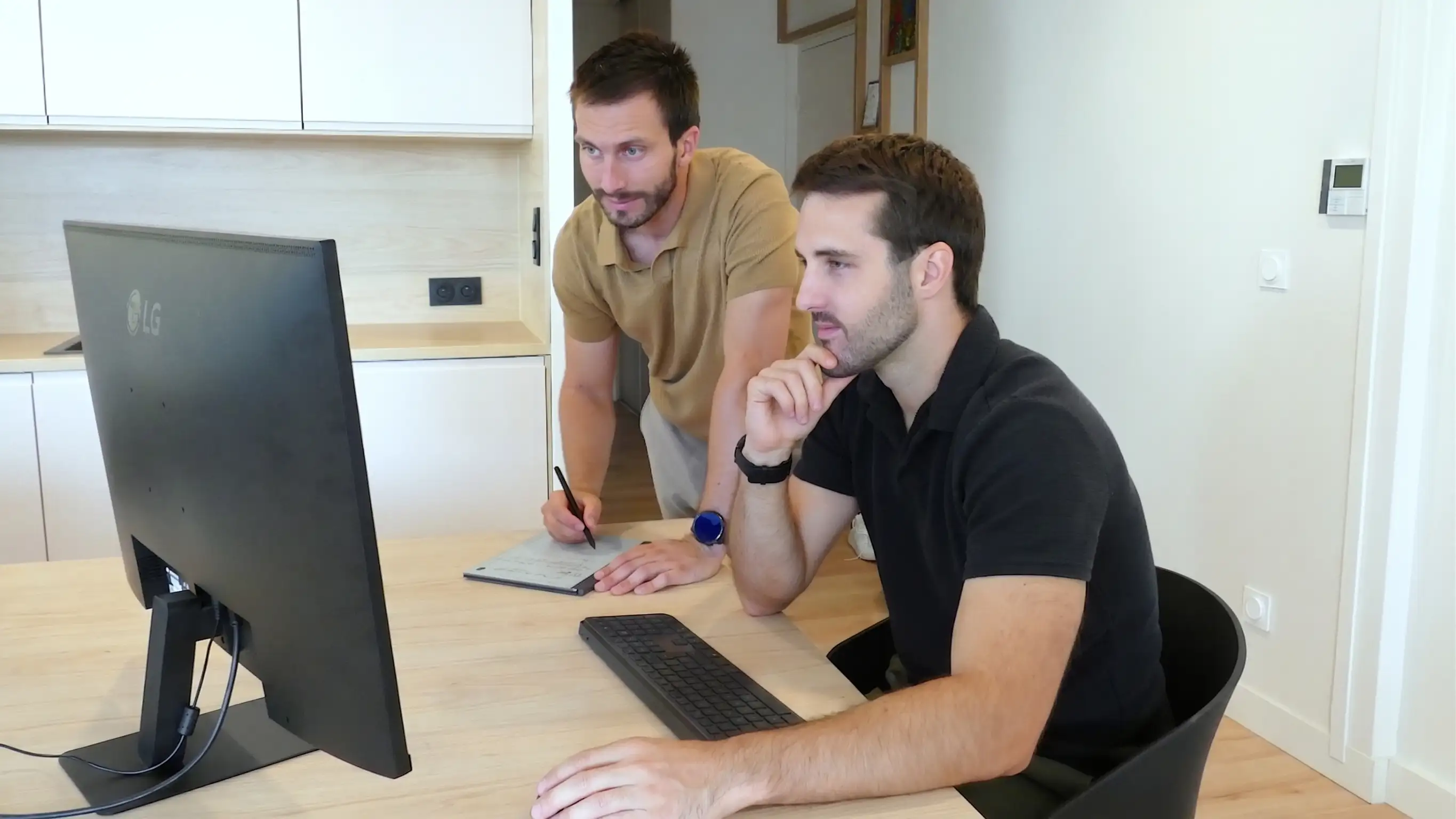 Les deux associés de Konsol devant un écran : l'un debout annote une tablette graphique, l'autre assis observe, la main sur le menton.